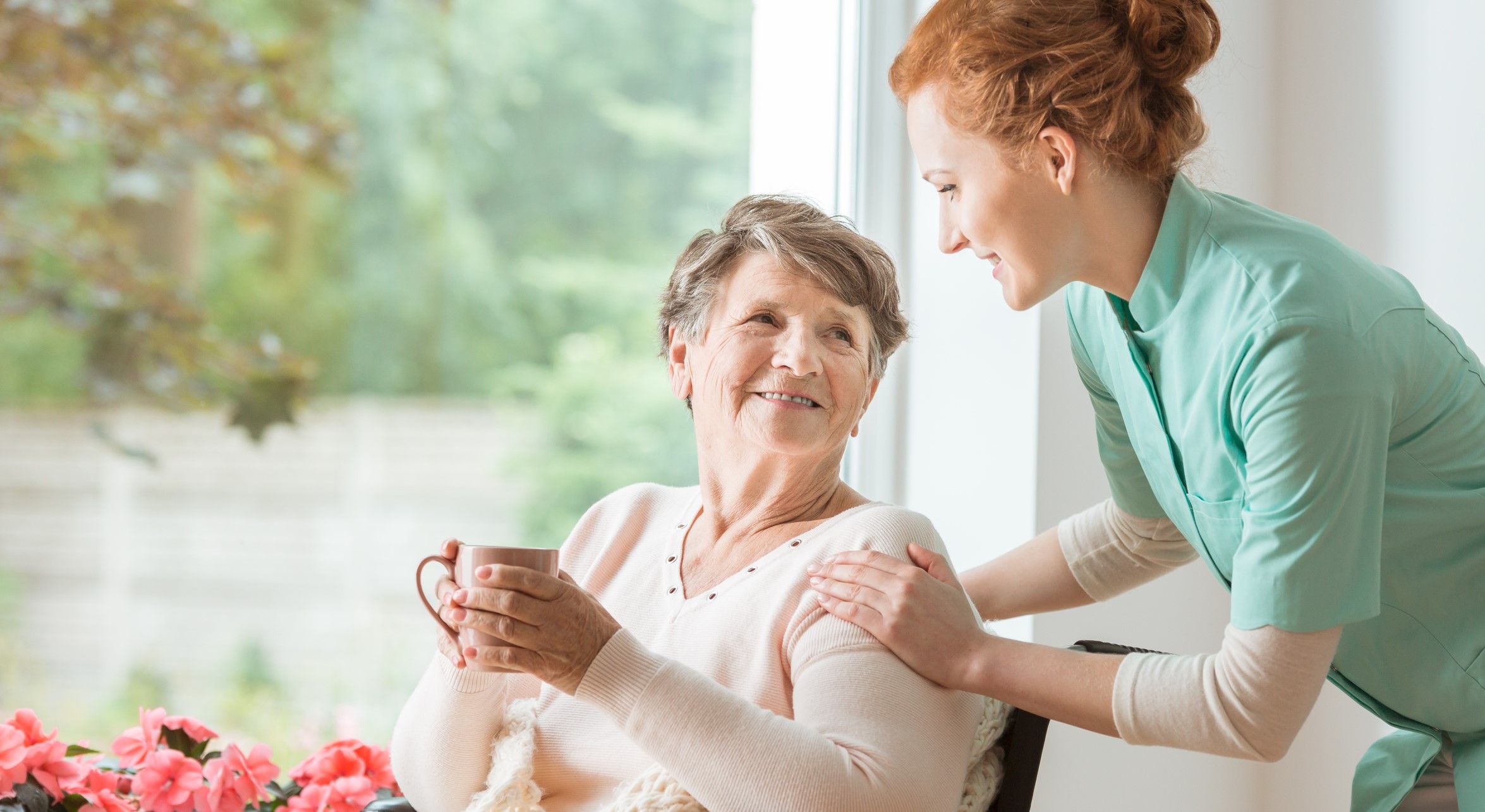 Pflegekraft spricht mit Oma im Rollstuhl